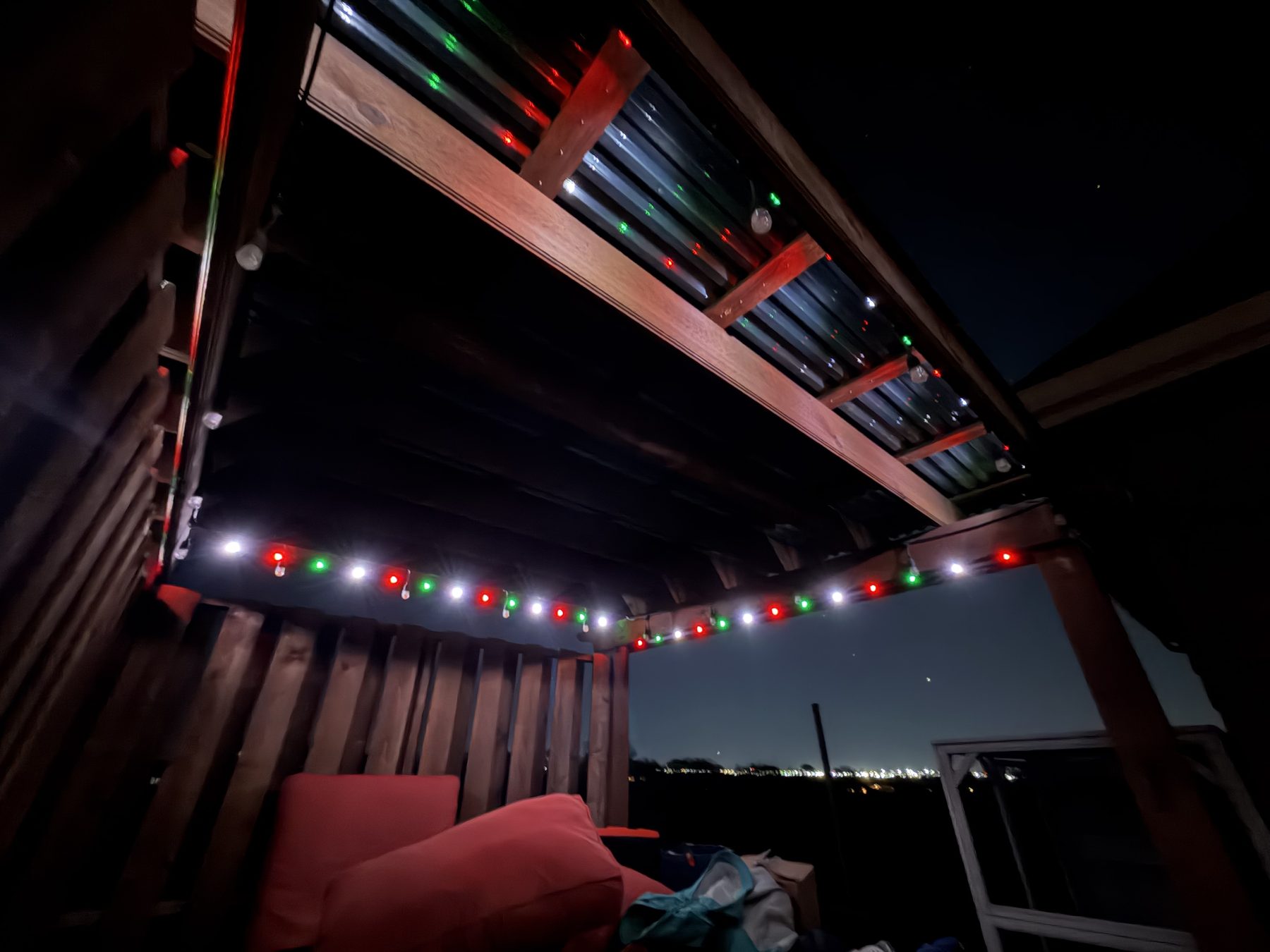 Pergola beams wrapped in red, green and white permanent lighting